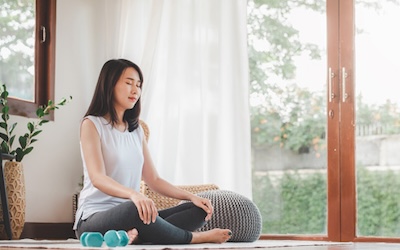 Asian woman doing yoga meditation at home